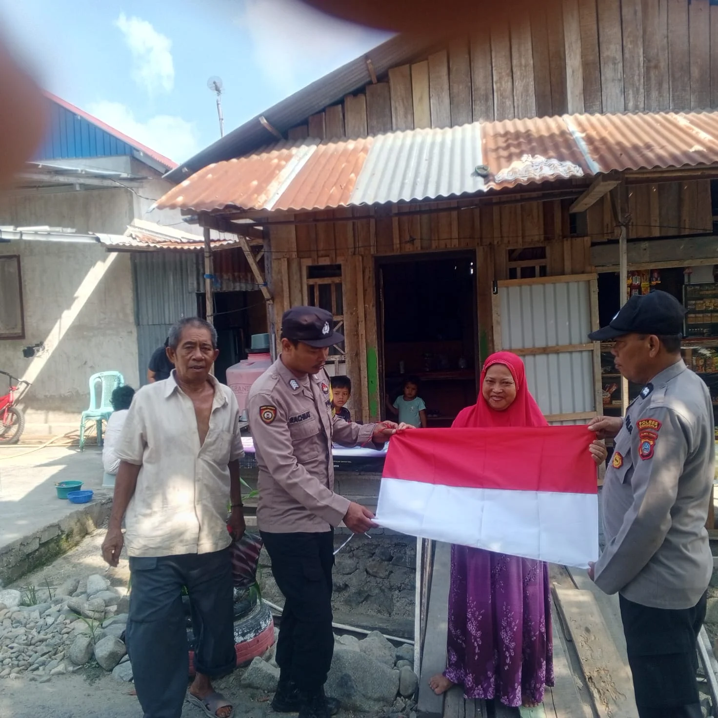 Kapolres Donggala, Melalui Kapolsek Labuan Iptu Umar Lahabe, S.Ap, Bagikan Bendera  Merah Putih Di Tempat - Keramaian, Desa Labuan  Pada  HUT RI Ke - 81 